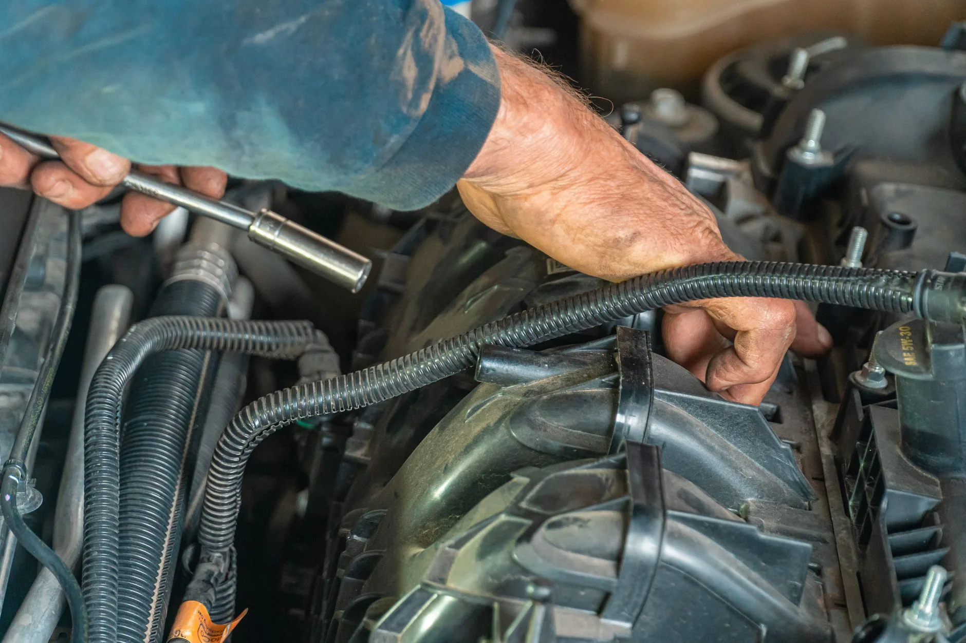 Manos de un mecánico reparando el motor de un coche.