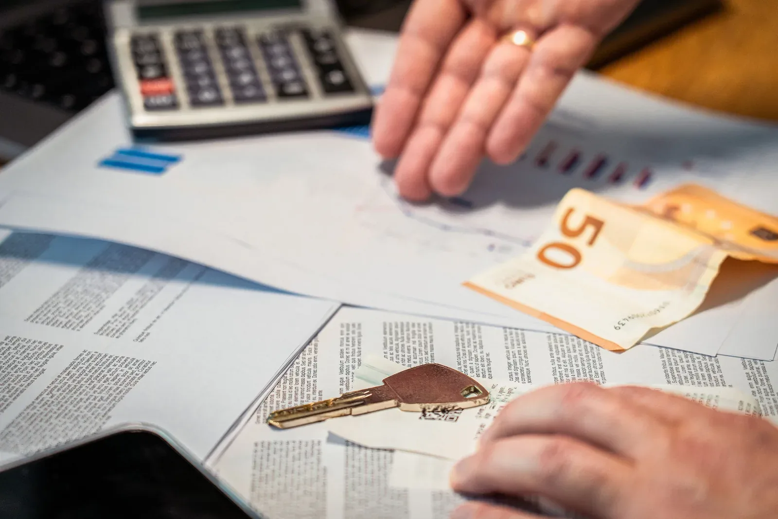Documentos, dinero y una llave sobre una mesa