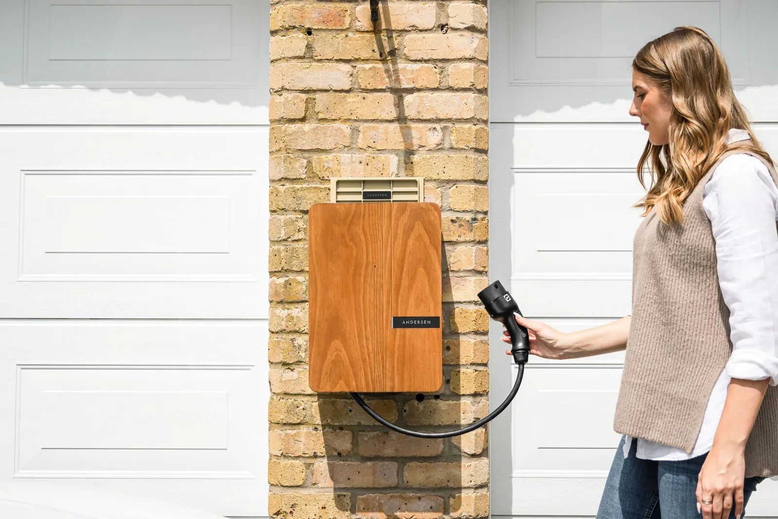 Persona conectando un cargador doméstico a un coche eléctrico