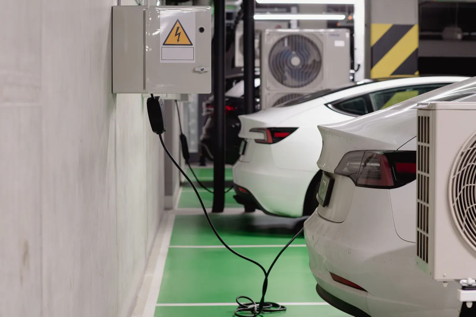 Vehículos eléctricos conectados a puntos de recarga en un garaje