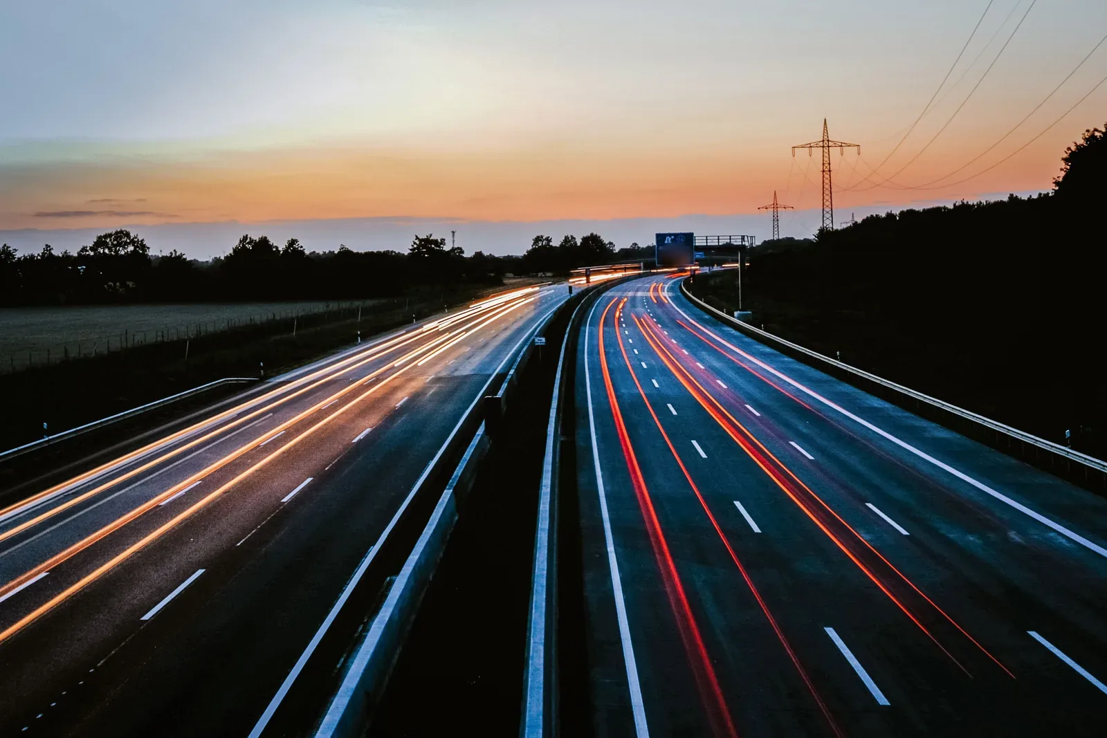 Stunning long exposure of light trails on a highway during dusk, showcasing movement and serene skies.